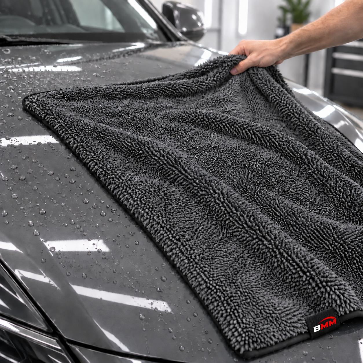Plush gray drying towel on a freshly washed car